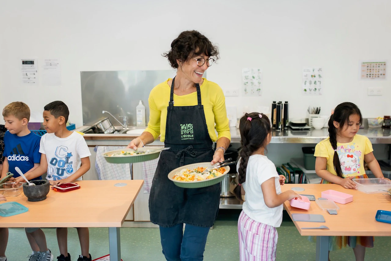Une femme vêtue d'un tablier porte deux plats de 